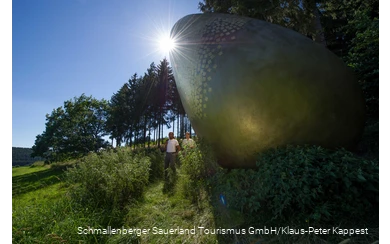 Zwei Wanderer am "goldenen Ei" auf dem WaldSkulpturen-Weg.