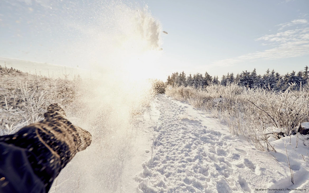 Eine Hand wirft Schnee in die Luft.