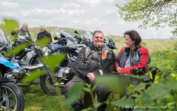 Motorradfahrer machen Pause auf einer Bank im Sauerland.