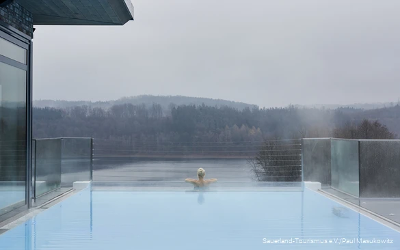 Eine Frau entspannt im Infinity-Pool eines Hotels.