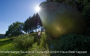 Zwei Wanderer am "goldenen Ei" auf dem WaldSkulpturen-Weg.