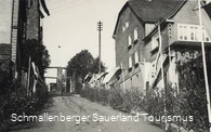 Blick von der Straße "Auf der Mauer" Richtung Kirche; im Hintergrund das Ehrenmal für die Gefallenen des 1. Weltkrieges, vor 1961. 