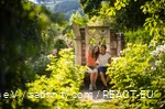 Mutter und Tochter sitzen in einem blühenden Garten und machen ein Selfie.